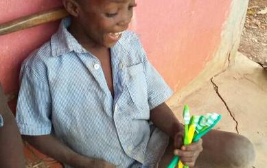 Young Haitian boy smiling with new toothbrushes